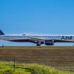 Jato da Embraer da Azul preparado para decolar em um aeroporto, sob céu ensolarado.