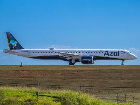 Jato da Embraer da Azul preparado para decolar em um aeroporto, sob céu ensolarado.