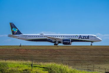 Jato da Embraer da Azul preparado para decolar em um aeroporto, sob céu ensolarado.