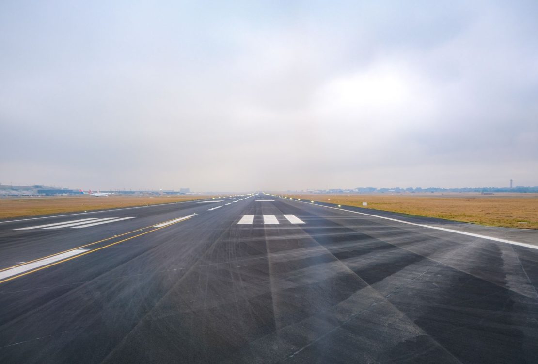 Vista longitudinal de uma pista de aeroporto vazia em um dia de pouca visibilidade.