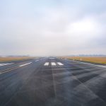 Vista longitudinal de uma pista de aeroporto vazia em um dia de pouca visibilidade.