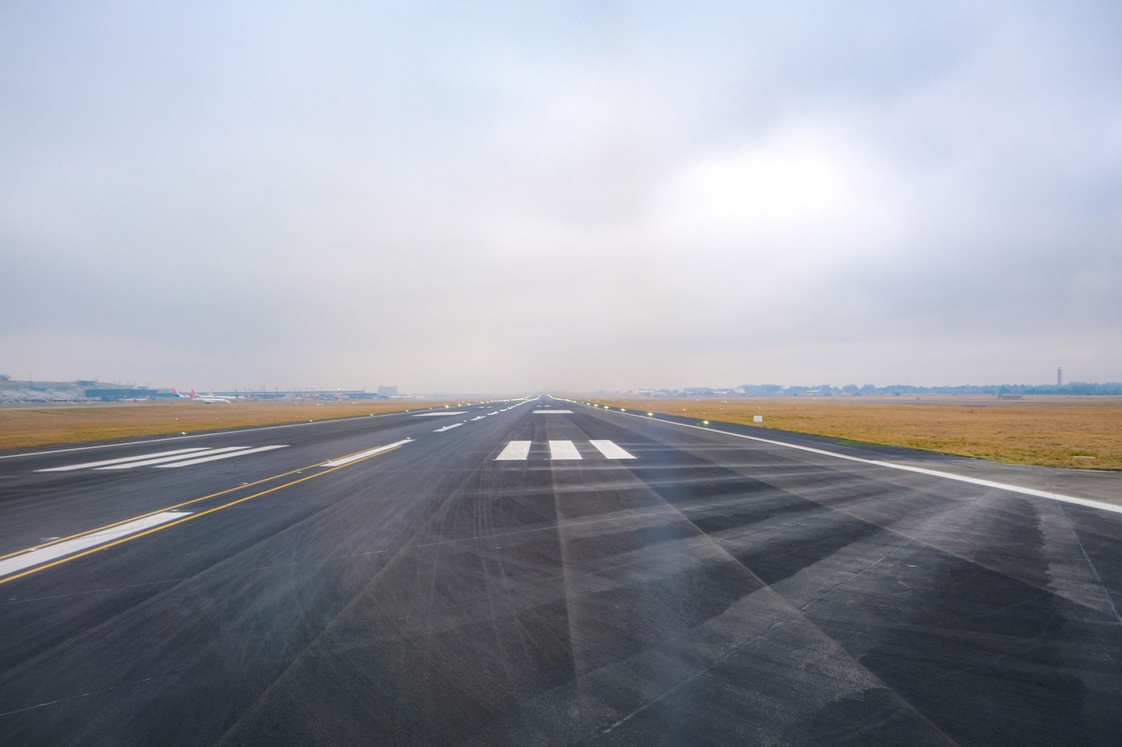 Vista longitudinal de uma pista de aeroporto vazia em um dia de pouca visibilidade.