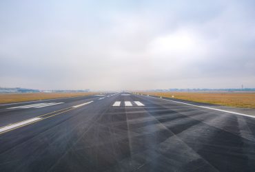 Vista longitudinal de uma pista de aeroporto vazia em um dia de pouca visibilidade.