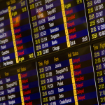 Painel digital de um aeroporto exibe informações sobre chegadas e partidas de voos.