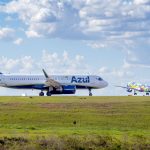 Aeronaves da Azul estacionadas ou em operação na pista de um aeroporto sob céu azul.