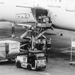 Carga sendo embarcada em um avião no pátio de um aeroporto.