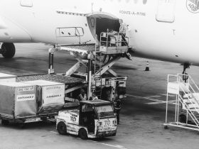 Carga sendo embarcada em um avião no pátio de um aeroporto.