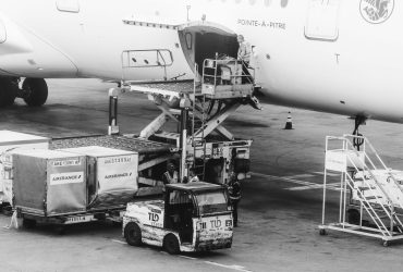 Carga sendo embarcada em um avião no pátio de um aeroporto.