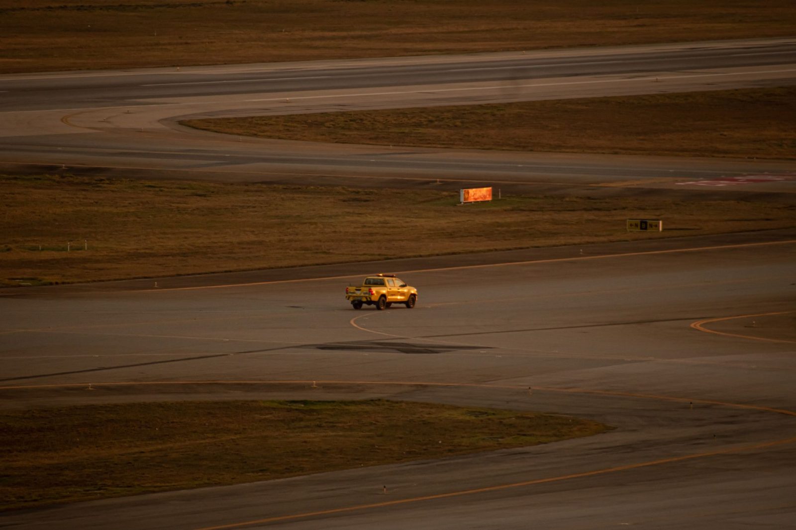 Picape amarela circula pela pista do Aeroporto Internacional de Guarulhos.
