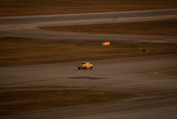 Picape amarela circula pela pista do Aeroporto Internacional de Guarulhos.