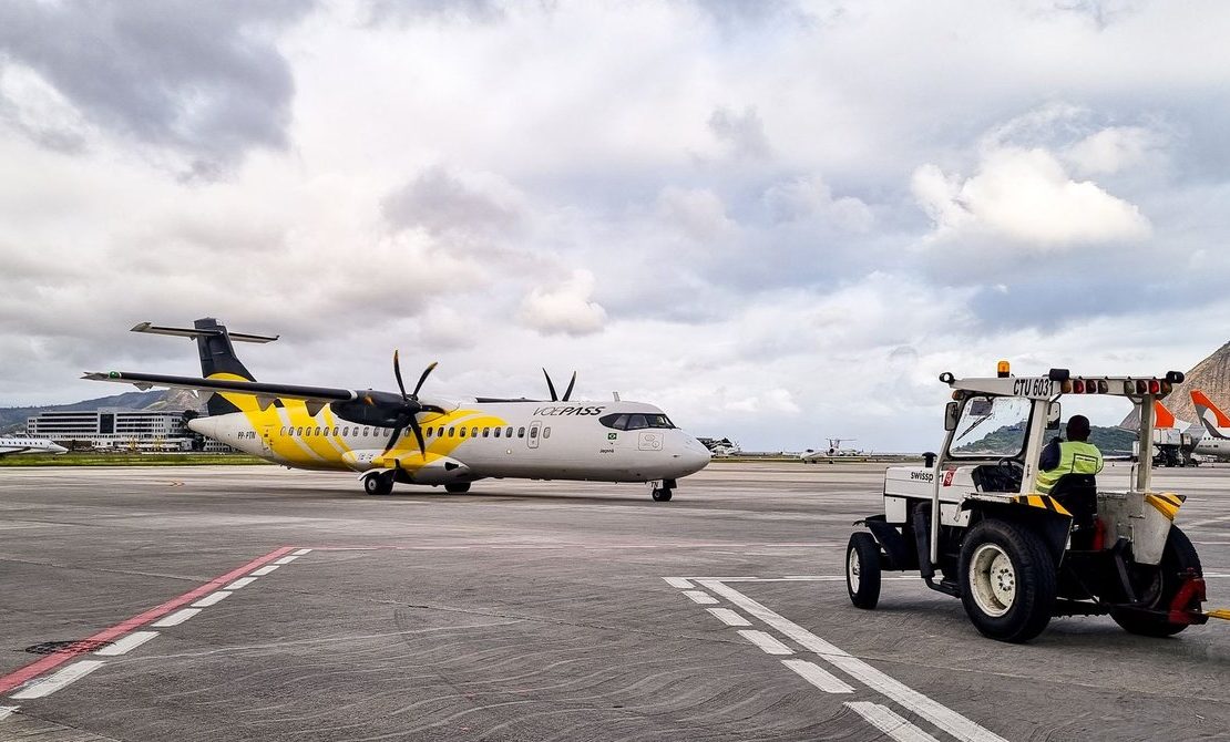 Aeronave turboélice na pista de um aeroporto no Rio de Janeiro, com equipe de solo auxiliando a operação.