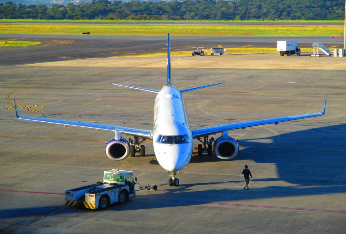 Avião comercial se prepara para decolar em um aeroporto de Minas Gerais, em dia claro.