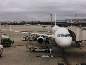 Avião sendo preparado em aeroporto de São Paulo junto a uma ponte de embarque e equipe de solo.