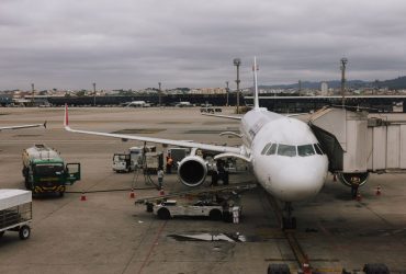 Avião sendo preparado em aeroporto de São Paulo junto a uma ponte de embarque e equipe de solo.