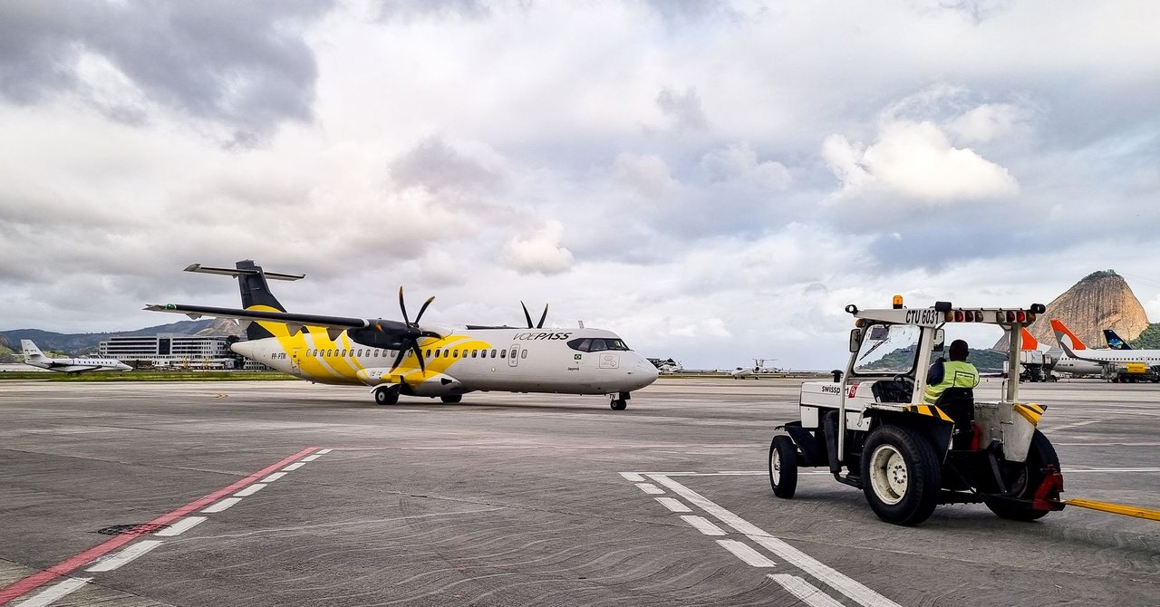Aeronave turboélice na pista de um aeroporto no Rio de Janeiro, com equipe de solo auxiliando a operação.
