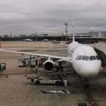 Aeronave comercial sendo preparada junto a uma ponte de embarque em um aeroporto de São Paulo, com equipe de solo no pátio.