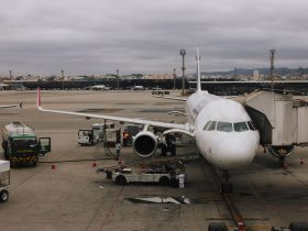Aeronave comercial sendo preparada junto a uma ponte de embarque em um aeroporto de São Paulo, com equipe de solo no pátio.